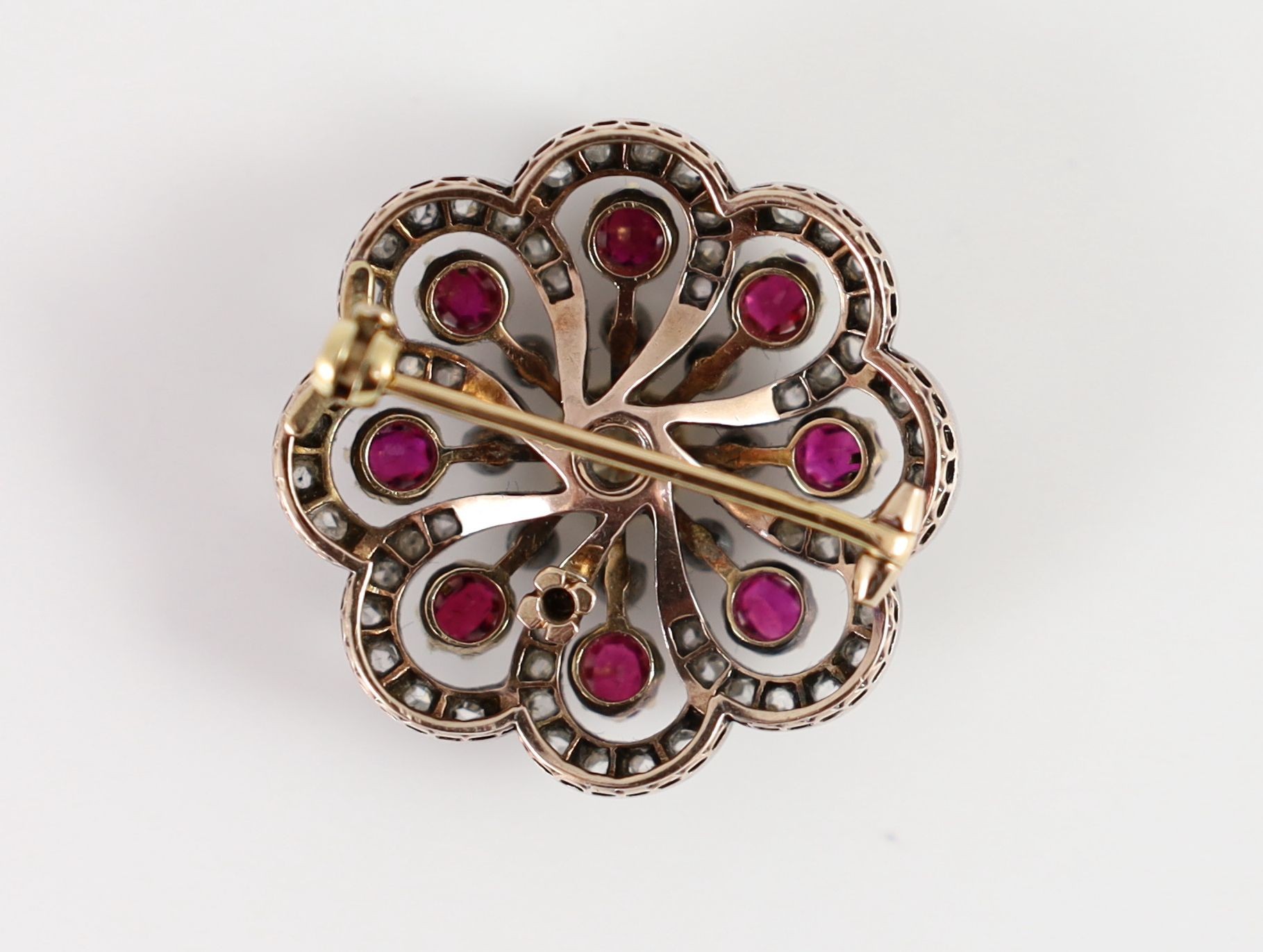 A late Victorian gold and silver, ruby and diamond set whorl shaped brooch